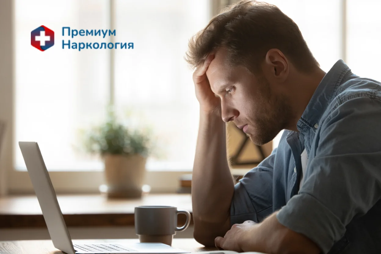 Уставший мужчина сидит днем за ноутбуком